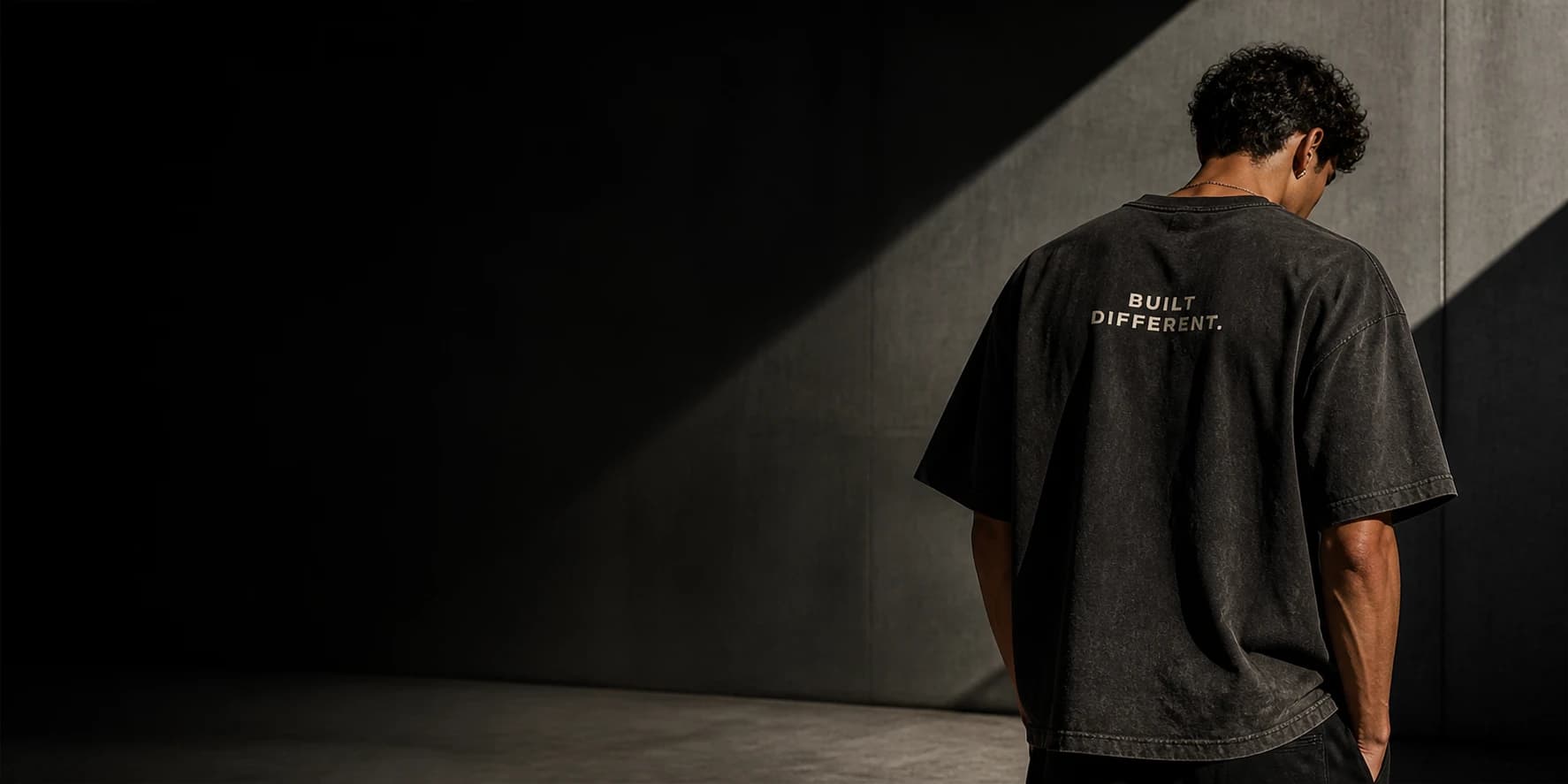 Model wearing a washed black SLAYFITS oversized tee against a concrete wall
